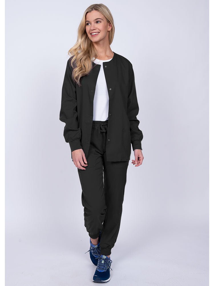 Woman wearing an Epic by MedWorks Women's Snap Front Scrub Jacket in black with rib knit cuffs.