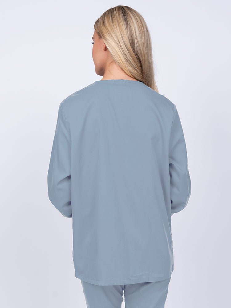 Young nurse wearing an Epic by MedWorks Women's Snap Front Scrub Jacket in blue fog featuring a missy fit & a round neck.