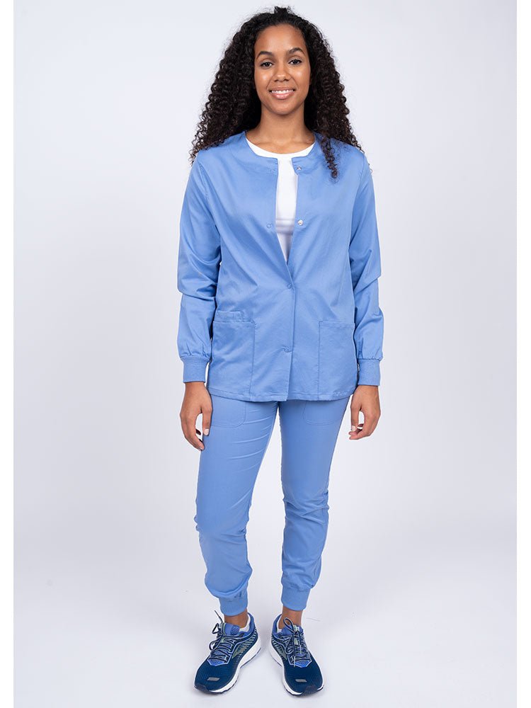 Woman wearing an Epic by MedWorks Women's Snap Front Scrub Jacket in ceil with rib knit cuffs.