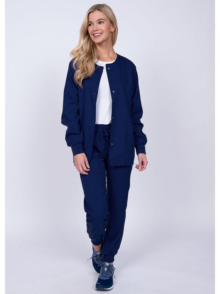 Woman wearing an Epic by MedWorks Women's Snap Front Scrub Jacket in navy with rib knit cuffs.