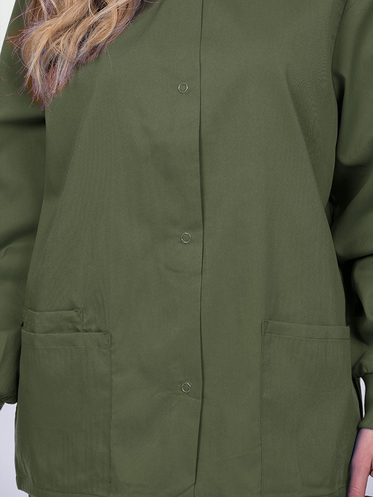 Young nurse wearing an Epic by MedWorks Women's Snap Front Scrub Jacket in olive with color matched metal snap closure.