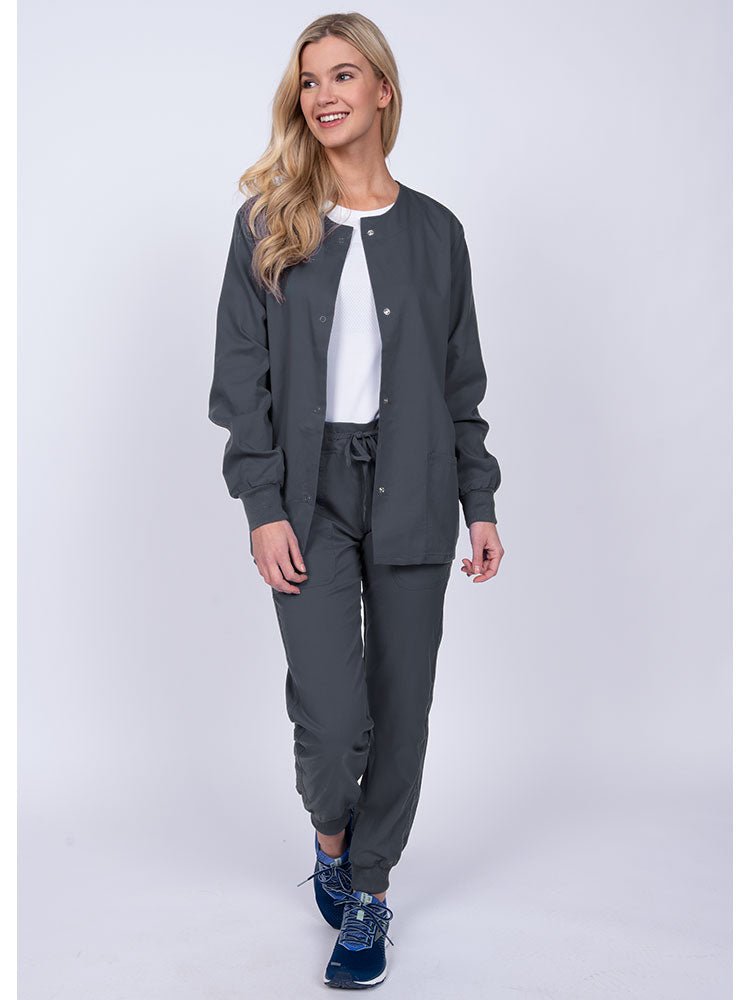 Woman wearing an Epic by MedWorks Women's Snap Front Scrub Jacket in pewter with rib knit cuffs.