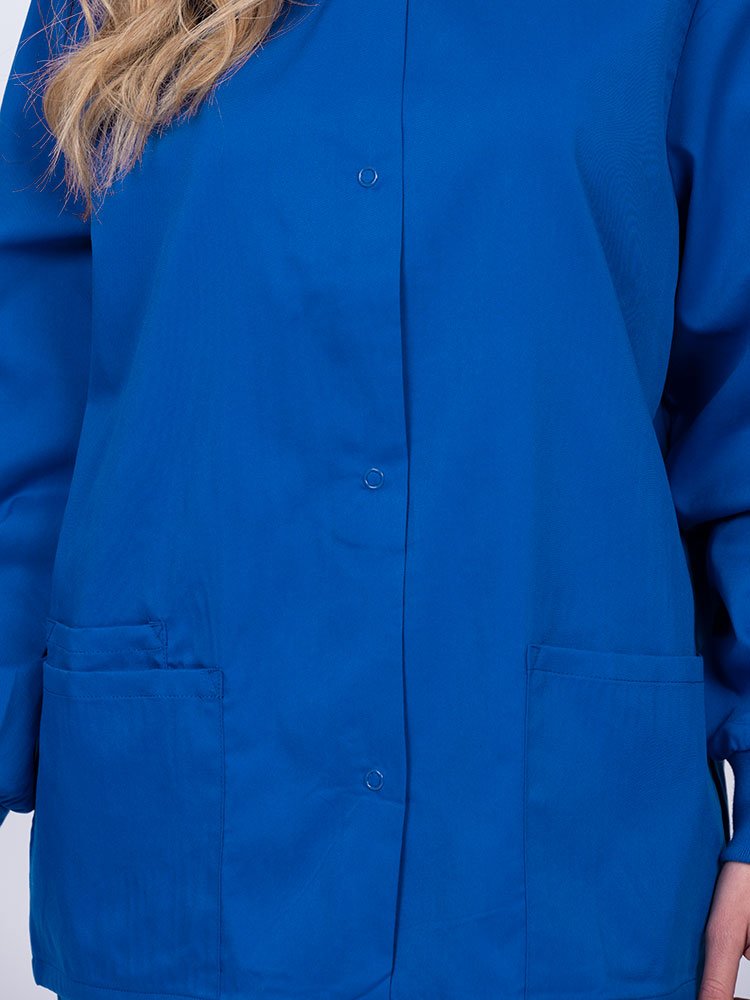 Young nurse wearing an Epic by MedWorks Women's Snap Front Scrub Jacket in royal with color matched metal snap closure.