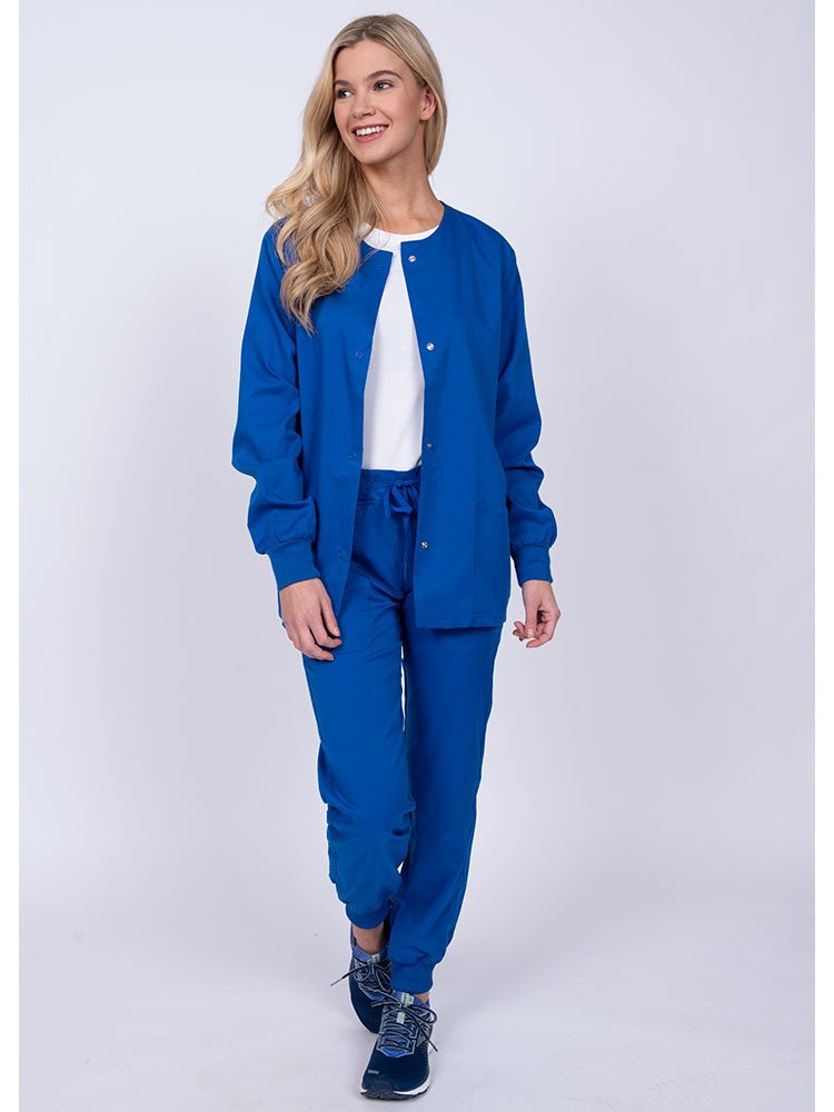 Woman wearing an Epic by MedWorks Women's Snap Front Scrub Jacket in royal with rib knit cuffs.