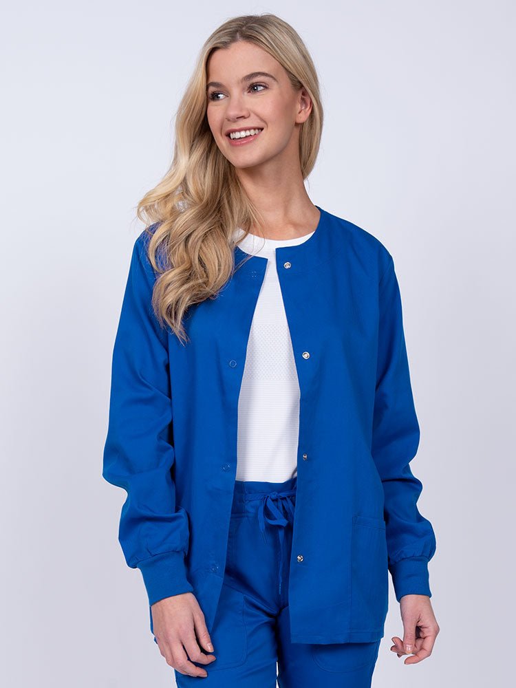 Young female healthcare worker wearing an Epic by MedWorks Women's Snap Front Scrub Jacket in royal with two front patch pockets.