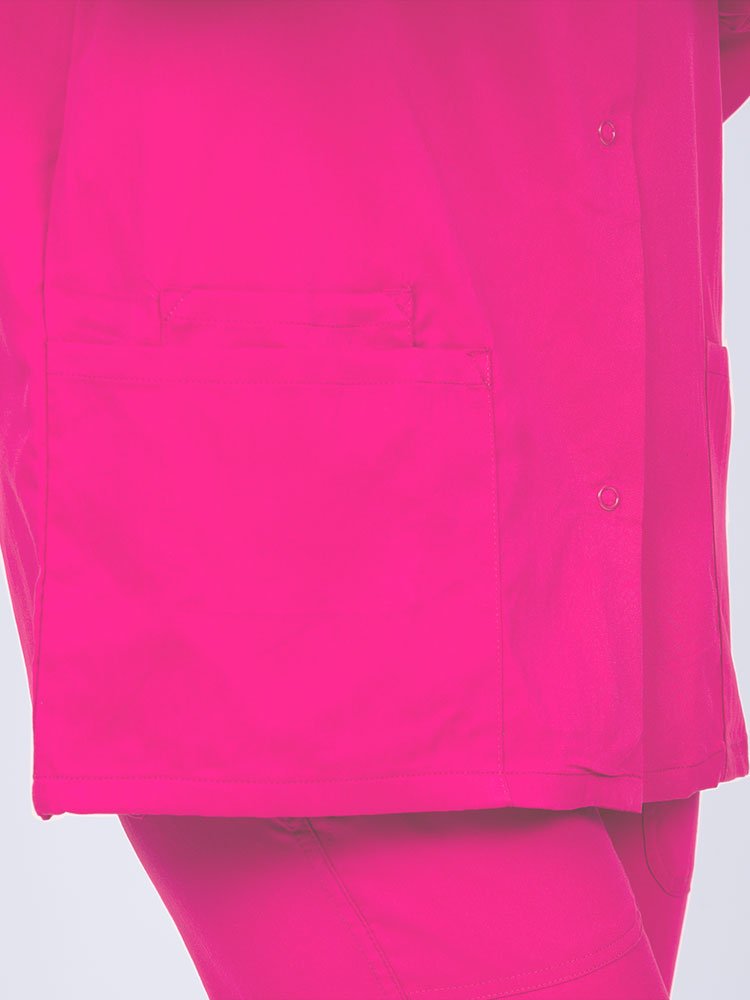 Young healthcare professional wearing an Epic by MedWorks Women's Snap Front Scrub Jacket in shocking pink with 1 interior cell phone pocket on wearer's right side.