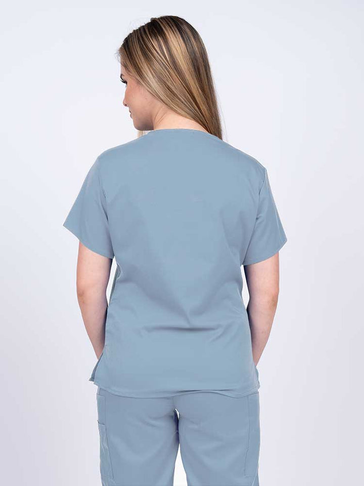 Woman wearing an Epic by MedWorks Women's Y-Neck Scrub Top in blue fog with a center back length of 26".