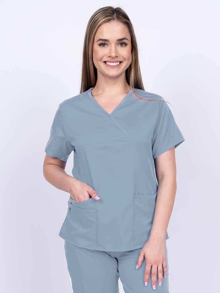 Woman wearing an Epic by MedWorks Women's Y-Neck Scrub Top in blue fog with a super soft, 2-way stretch fabric designed to move with your body all day long.