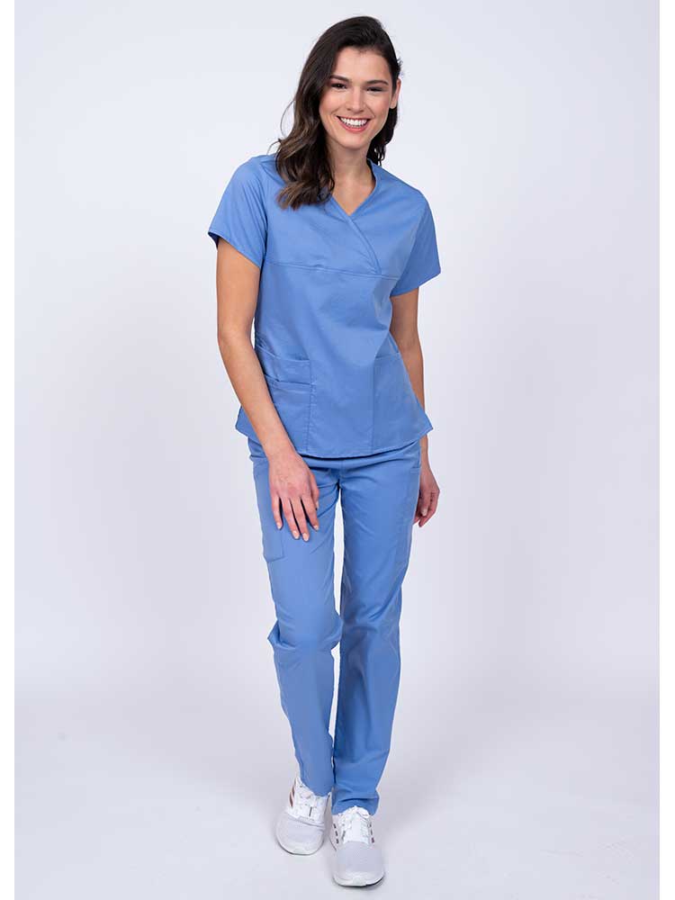 Young woman wearing an Epic by MedWorks Women's Y-Neck Scrub Top in ceil with 2 front patch pockets.