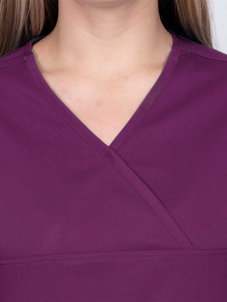 Woman wearing an Epic by MedWorks Women's Scrub Top in eggplant with a Y-neckline.