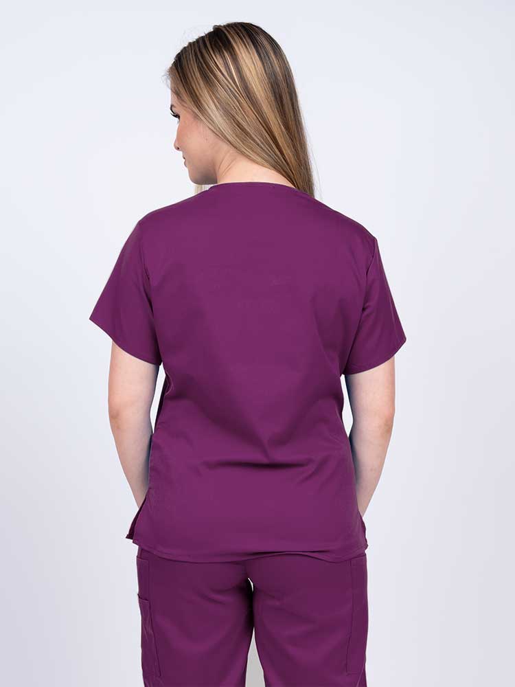 Woman wearing an Epic by MedWorks Women's Y-Neck Scrub Top in eggplant with a center back length of 26".