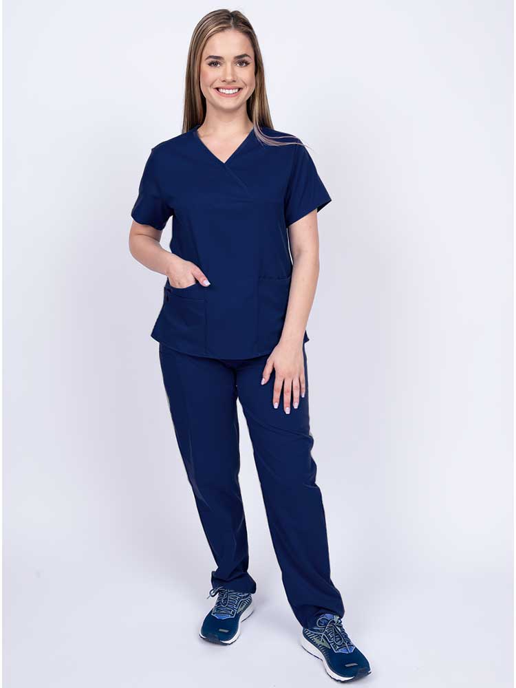 Young woman wearing an Epic by MedWorks Women's Y-Neck Scrub Top in navy with 2 front patch pockets.