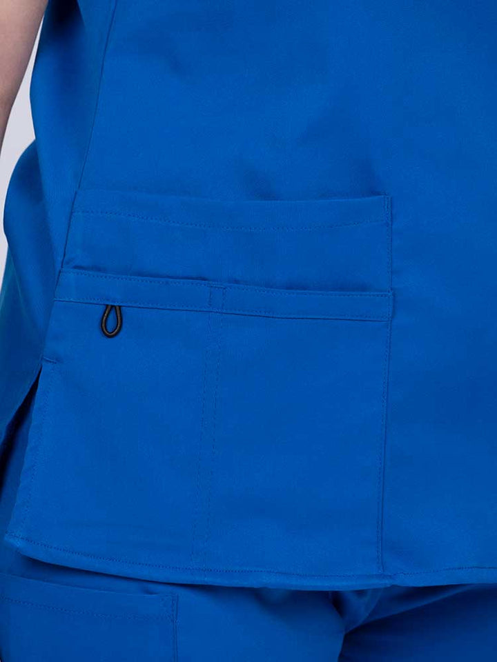 Young female healthcare worker wearing an Epic by MedWorks Women's Y-Neck Scrub Top in royal with 1 double outer pocket on the wearer's right side.