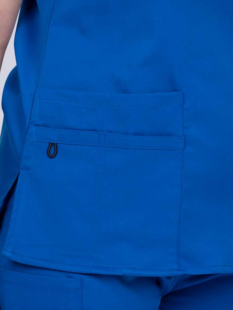 Young female healthcare worker wearing an Epic by MedWorks Women's Y-Neck Scrub Top in royal with 1 double outer pocket on the wearer's right side.
