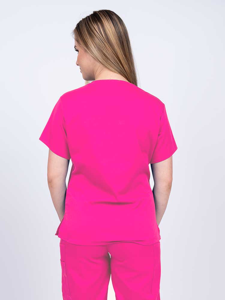 Woman wearing an Epic by MedWorks Women's Y-Neck Scrub Top in shocking pink with a center back length of 26".
