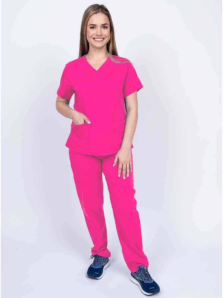 Young woman wearing an Epic by MedWorks Women's Y-Neck Scrub Top in shocking pink with 2 front patch pockets.