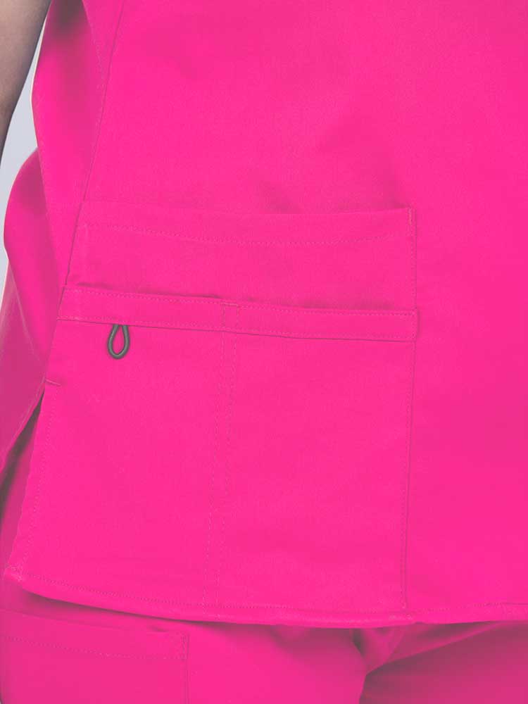Young female healthcare worker wearing an Epic by MedWorks Women's Y-Neck Scrub Top in shocking pink with 1 double outer pocket on the wearer's right side.