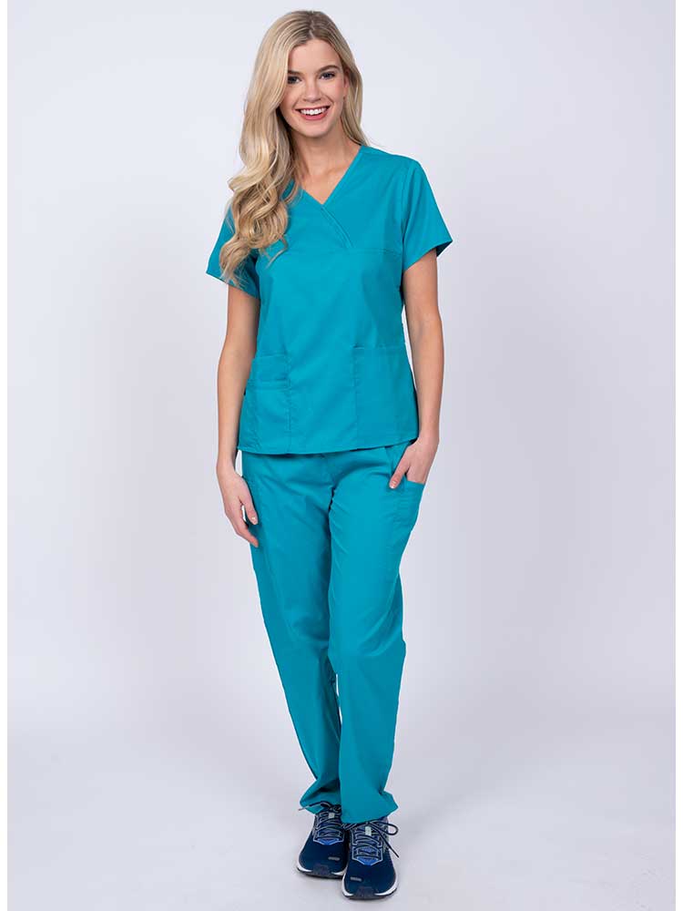 Young woman wearing an Epic by MedWorks Women's Y-Neck Scrub Top in blue fog with 2 front patch pockets.