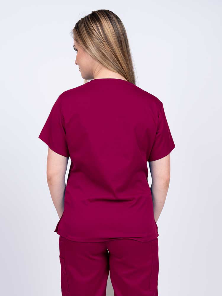 Woman wearing an Epic by MedWorks Women's Y-Neck Scrub Top in wine with a center back length of 26".