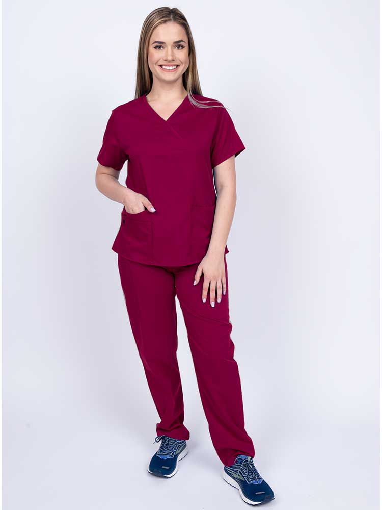 Young woman wearing an Epic by MedWorks Women's Y-Neck Scrub Top in wine with 2 front patch pockets.