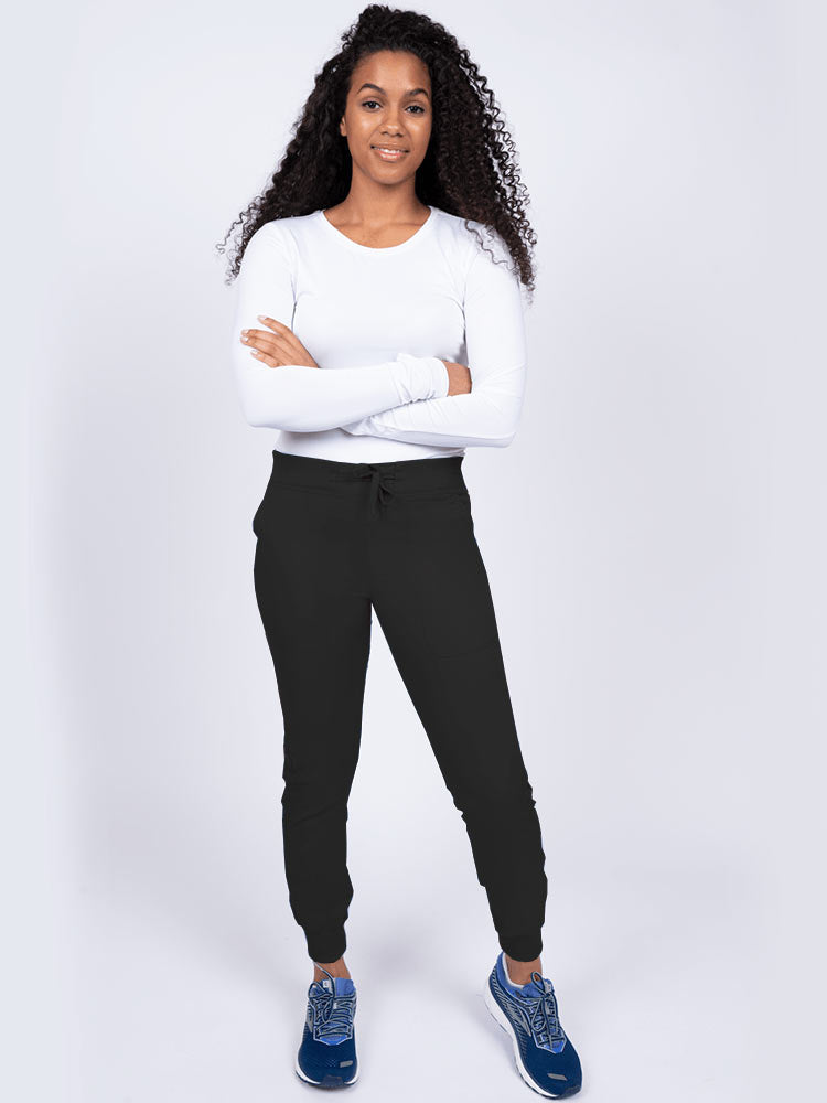 A young lady nurse wearing an Epic by MedWorks Women's Yoga Jogger Scrub Pant in Black size Large Petite featuring stylish cover stitch detail throughout.