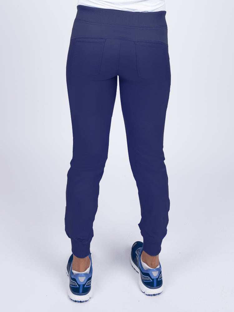 A young female Nurse Practitioner wearing an Epic by MedWorks Women's Yoga Jogger Scrub Pant in Navy size small featuring 2 back patch pockets.