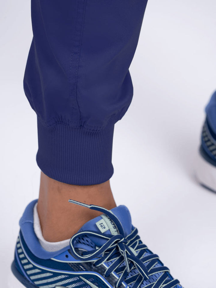 A young female LPN wearing an Epic by MedWorks Women's Yoga Jogger Scrub Pant in Navy featuring elastic rib knit ankle cuffs.