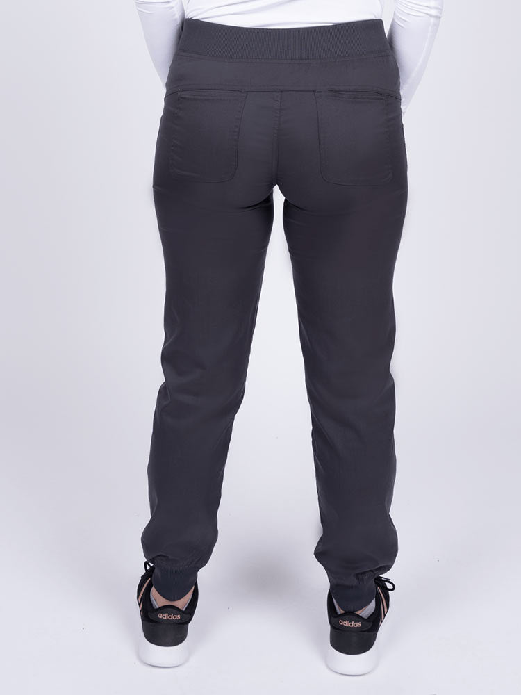A young female Nurse Practitioner wearing an Epic by MedWorks Women's Yoga Jogger Scrub Pant in Pewter size small featuring 2 back patch pockets.
