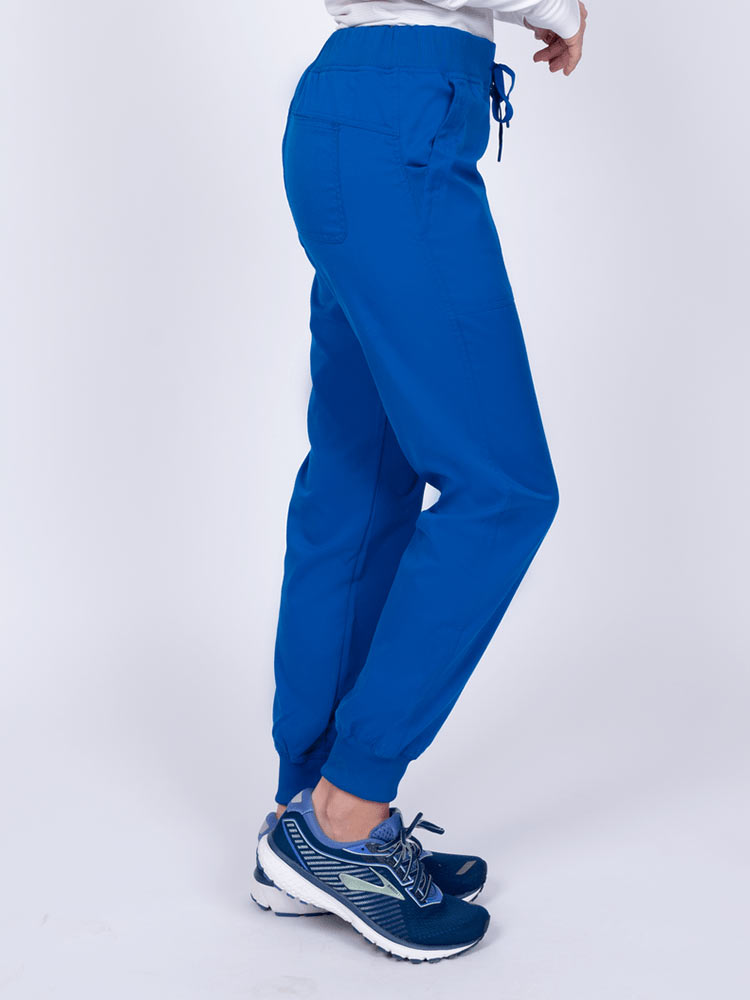 A female healthcare professional wearing the Epic by MedWorks Women's Yoga Jogger Scrub Pants in Royal size Large Tall featuring 2 slanted entry patch pockets on the front.