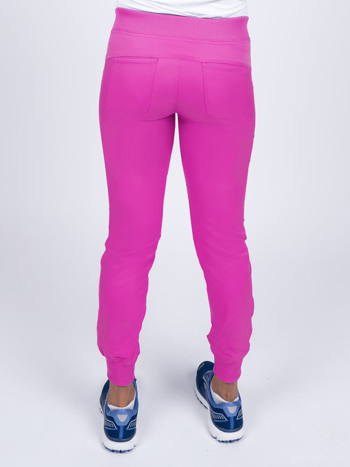 A young female Nurse Practitioner wearing an Epic by MedWorks Women's Yoga Jogger Scrub Pant in Shocking Pink size small featuring 2 back patch pockets.