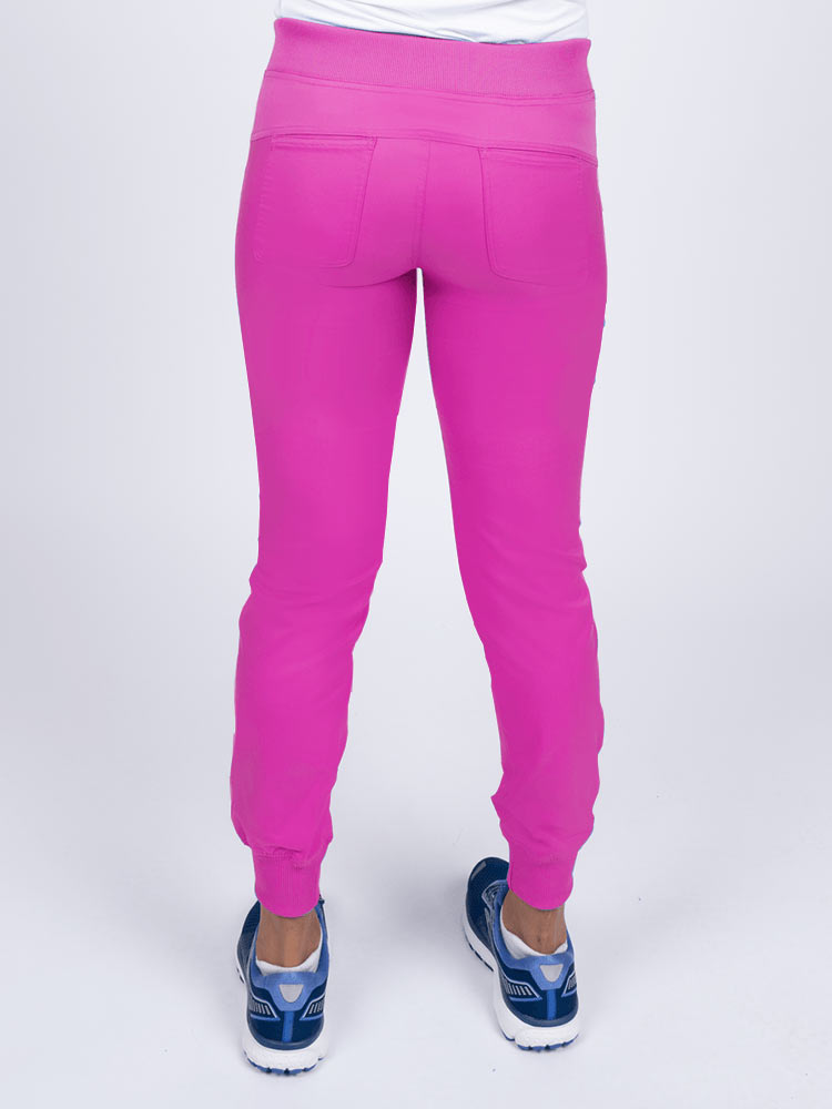 A young female Nurse Practitioner wearing an Epic by MedWorks Women's Yoga Jogger Scrub Pant in Shocking Pink size small featuring 2 back patch pockets.