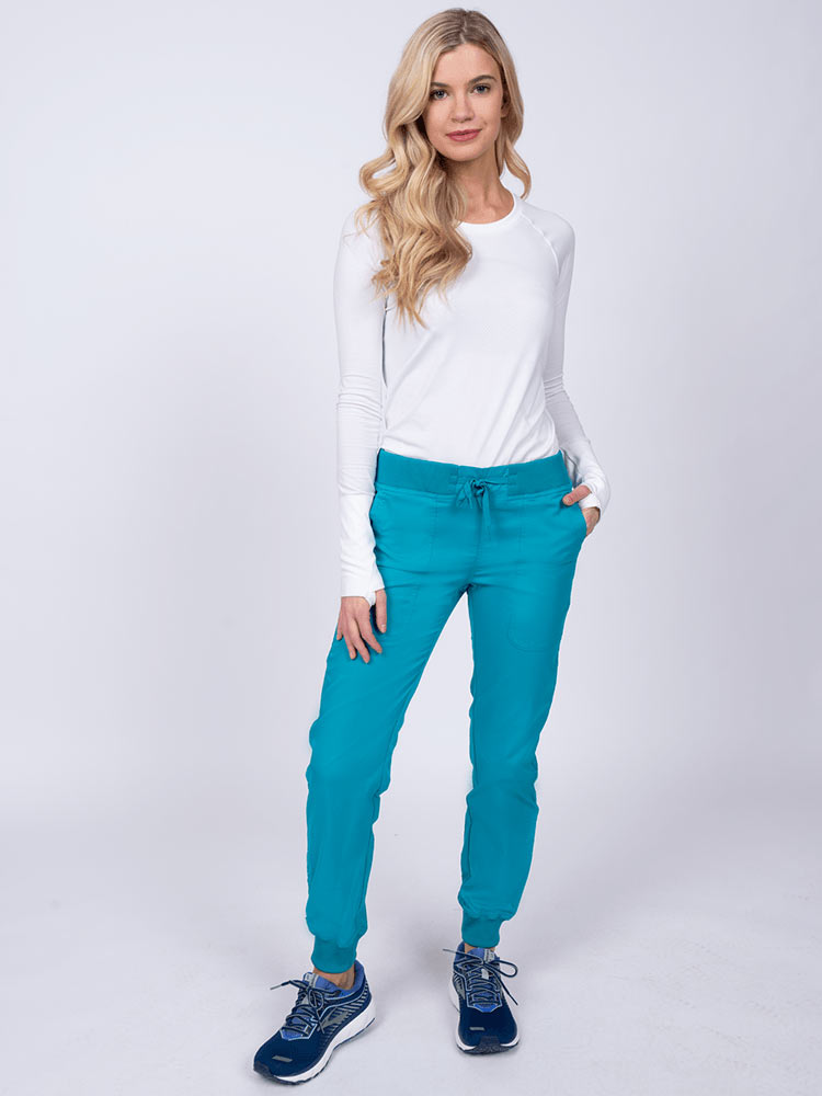 A young lady nurse wearing an Epic by MedWorks Women's Yoga Jogger Scrub Pant in Teal size Large Petite featuring stylish cover stitch detail throughout.