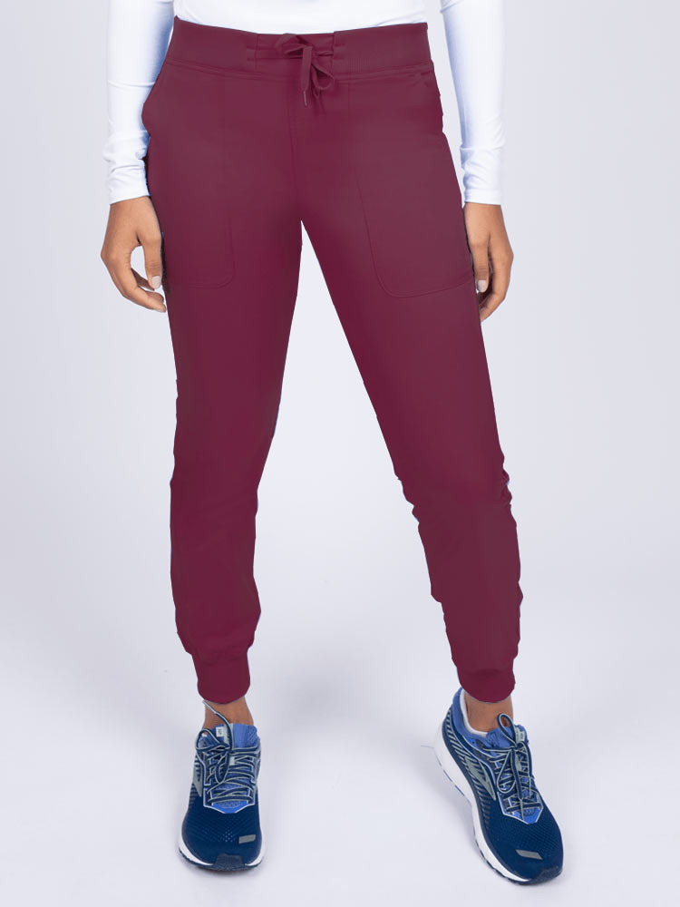 A young female Phlebotomist wearing an Epic by MedWorks Women's Yoga Jogger Scrub Pant in Wine size 3XL featuring a contemporary fit.