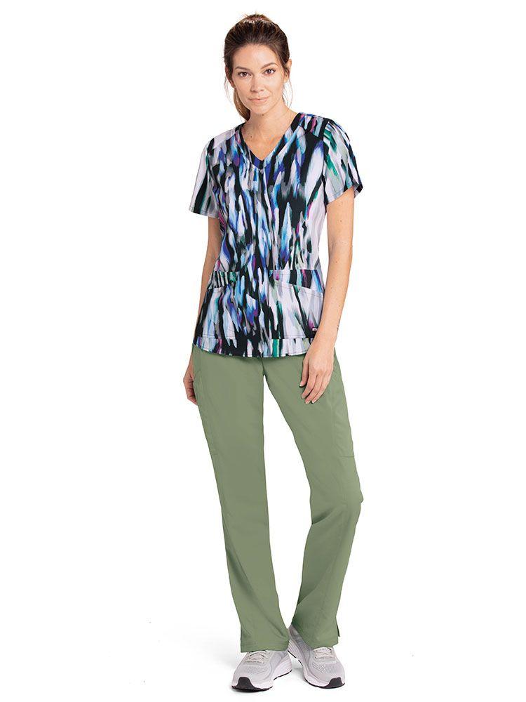 A young female Psychiatric Nurse wearing a Grey's Anatomy Women's Printed Scrub Top in Silver Cascades featuring a v-neckline and short sleeves.