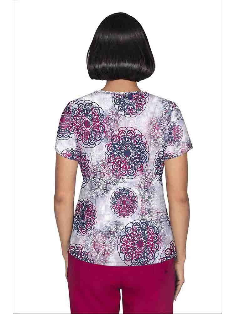 A young female Psychiatric Nurse wearing a Premiere by Healing Hands Women's Isabel Printed Scrub Top in "Dreamy Lace" size Medium featuring a center back length of 26.5".