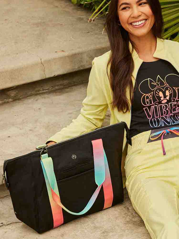 A young female healthcare professional using a HeartSoul Madison Duffel Bag in Black with Rainbow Straps.
