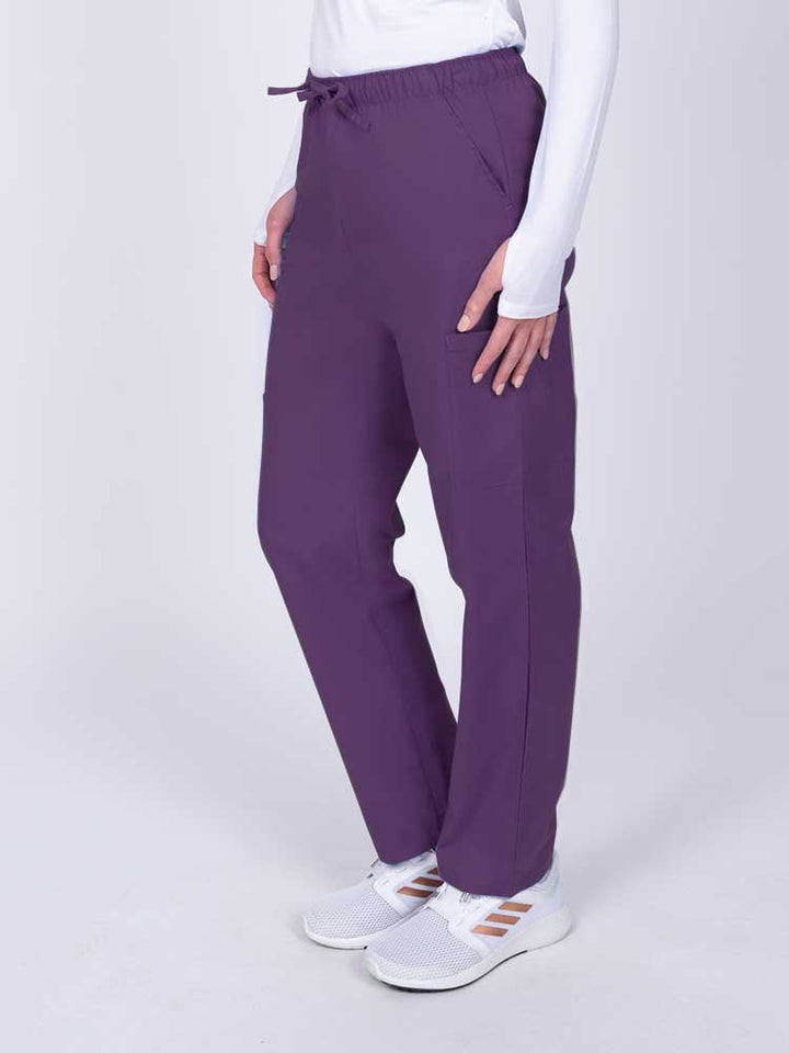 Woman wearing a Luv Scrubs by MedWorks Women's Elastic Waist Cargo Pant in eggplant with 2 front slash pockets.