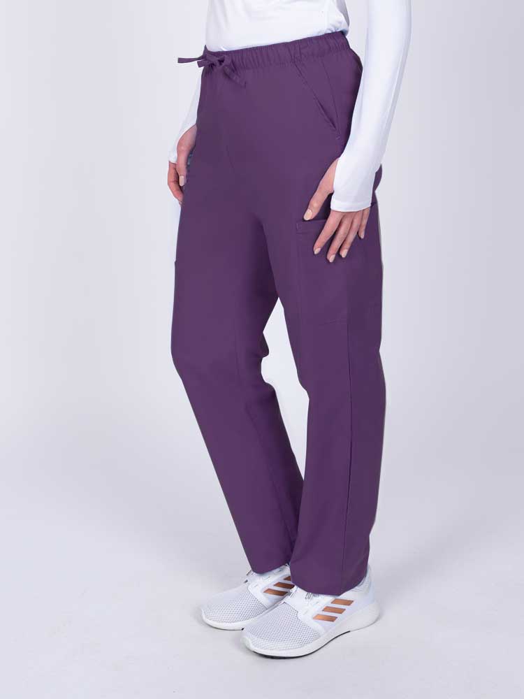 Woman wearing a Luv Scrubs by MedWorks Women's Elastic Waist Cargo Pant in eggplant with 2 front slash pockets.