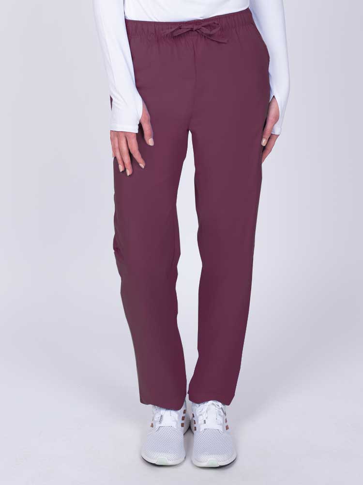 Young woman wearing a Luv Scrubs by MedWorks Women's Elastic Waist Cargo Pant in wine featuring one cargo pocket on the wearer's left side.
