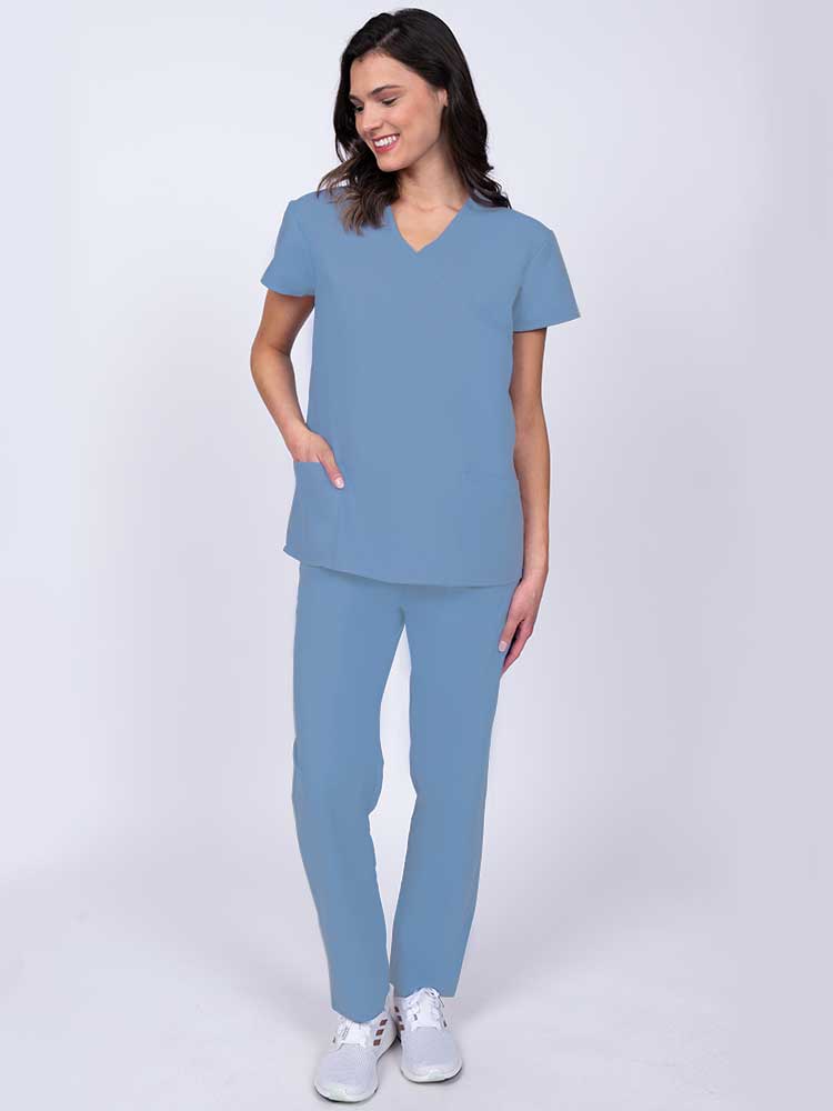 Young healthcare worker wearing a Luv Scrubs by MedWorks Women's Mock Wrap Scrub Top in ceil with 2 front patch pockets.