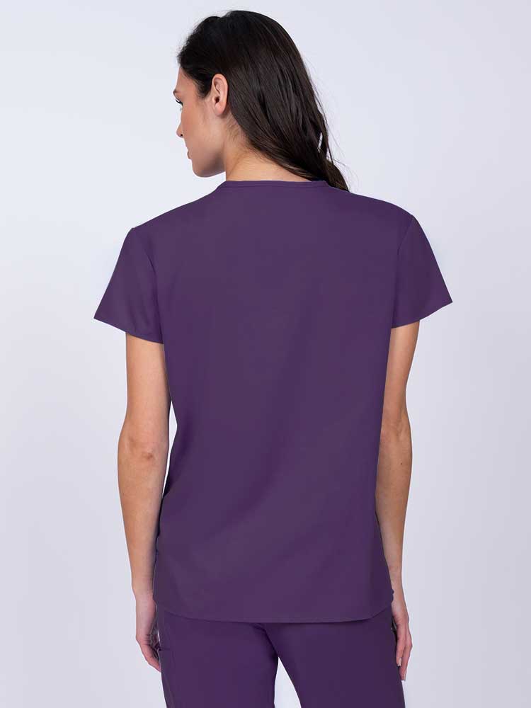Nurse wearing a Luv Scrubs by MedWorks Women's Mock Wrap Scrub Top in eggplant with shoulder yokes to ensure a flattering fit.