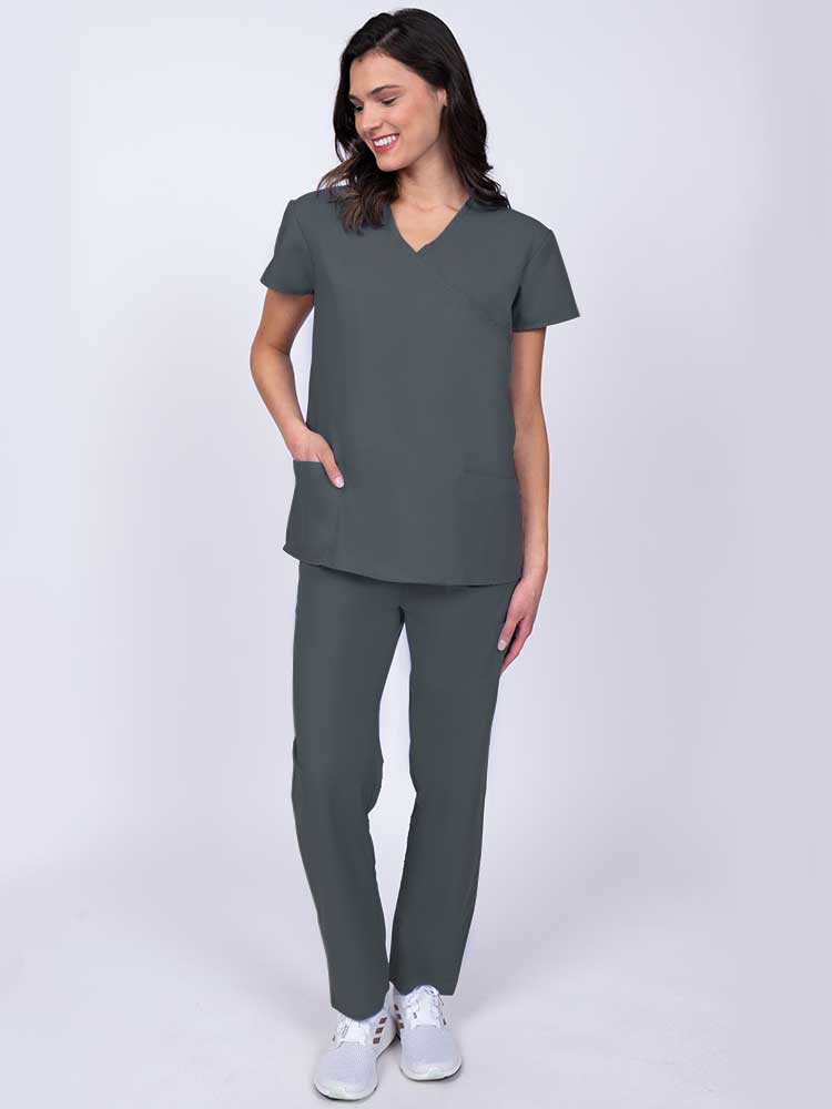 Young healthcare worker wearing a Luv Scrubs by MedWorks Women's Mock Wrap Scrub Top in pewter with 2 front patch pockets.