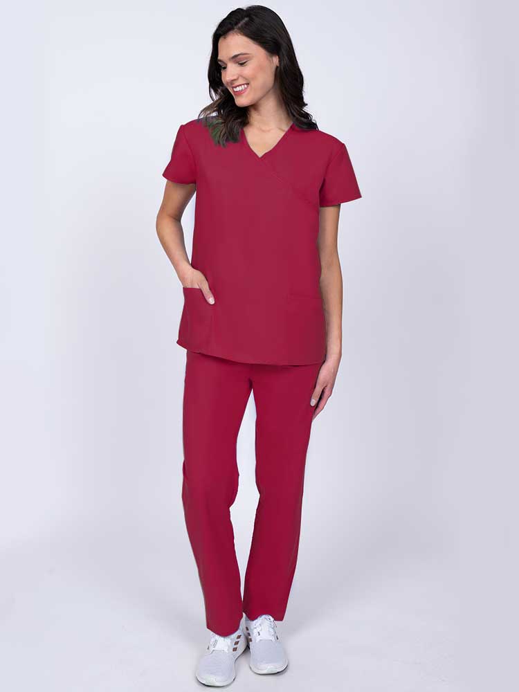 Young healthcare worker wearing a Luv Scrubs by MedWorks Women's Mock Wrap Scrub Top in red with 2 front patch pockets.