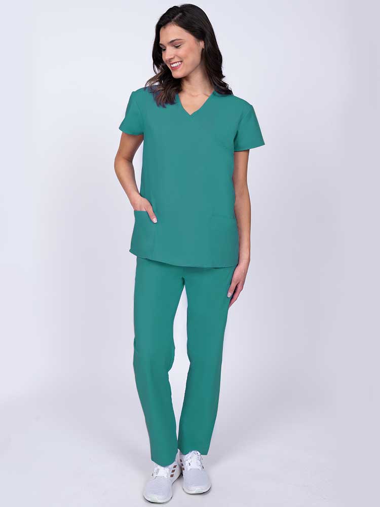 Young healthcare worker wearing a Luv Scrubs by MedWorks Women's Mock Wrap Scrub Top in teal with 2 front patch pockets.