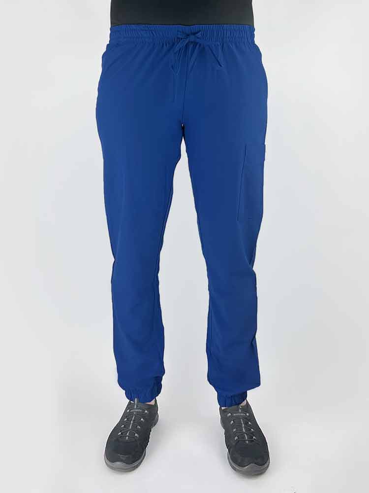Young female healthcare worker wearing a Luv Scrubs by MedWorks Women's Scrub Jogger in royal with 2 front slash pockets & 1 cargo pocket on wearer's left leg.