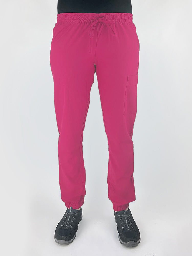 Young female healthcare worker wearing a Luv Scrubs by MedWorks Women's Scrub Jogger in shocking pink with 2 front slash pockets & 1 cargo pocket on wearer's left leg.