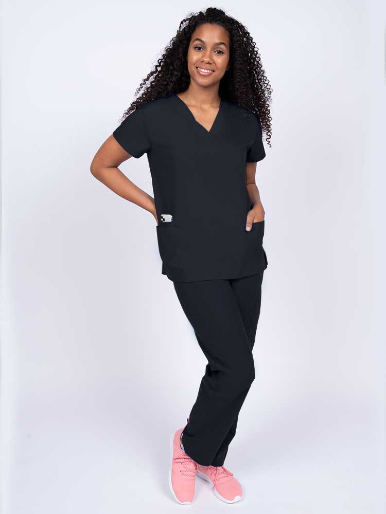 Woman wearing a Luv Scrubs by MedWorks Women's V-neck Scrub Top in black with 2 front patch pockets.