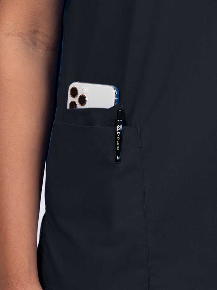 Young female healthcare worker wearing a  Luv Scrubs by MedWorks Women's V-neck Scrub Top  in black with a hidden utility pocket/pen slot on wearer's right side.