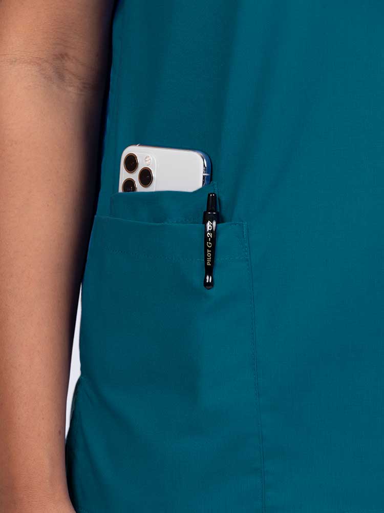 Young female healthcare worker wearing a Luv Scrubs by MedWorks Women's V-neck Scrub Top in Caribbean with a hidden utility pocket/pen slot on wearer's right side.