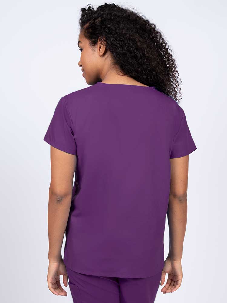 Woman wearing a Luv Scrubs by MedWorks Women's V-neck Scrub Top in eggplant with a center back length of 26".